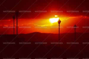 A street light in front of the setting sun.