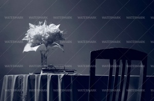A vase of flowers on the table with a chair