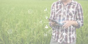 A man holding a tablet in front of a field.