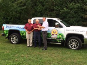 Three men standing in front of a green truck.