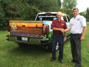 Two men shaking hands in front of a truck.