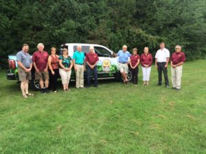 A group of people standing in front of a truck.