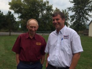 Two men standing next to each other in a field.