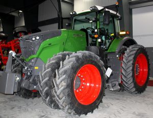 A green and red tractor is parked in a garage.