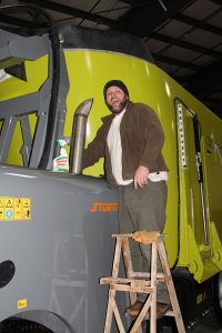 A man standing on a ladder next to a truck.