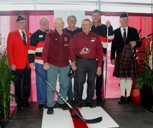 A group of men posing with a hockey stick.