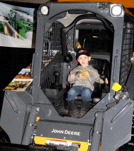 A little boy sitting in a john deere tractor.