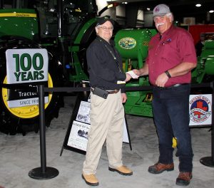 Two men standing in front of a john deere tractor.