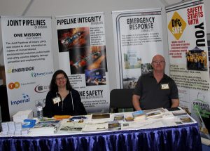 A man and woman sitting at a table at a trade show.