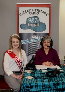 Two women sitting at a table in front of a microphone.