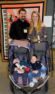 A family posing in front of a quilt.