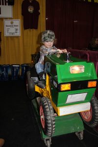 A child is riding a toy tractor.