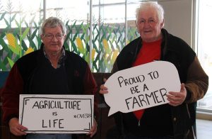 Two men holding signs that say agriculturist is a life and agriculturist is a way of life.