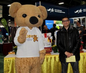 A man standing next to a teddy bear mascot.