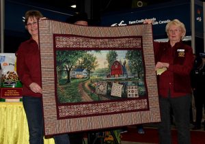 Two women holding up a quilt.