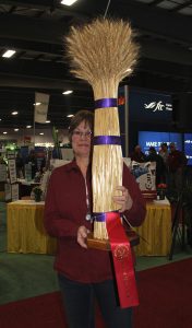 A woman holding a large straw hat with a ribbon.