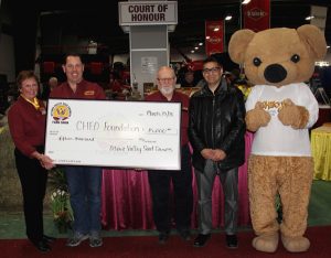 A group of people posing with a teddy bear.