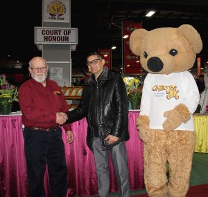 A man shaking hands with a teddy bear.
