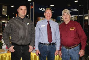 Three men standing next to each other at a trade show.