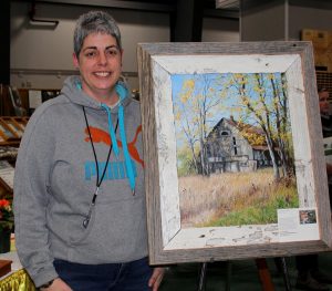 A woman standing next to a painting.