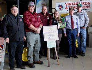 A group of people standing in front of a tractor.