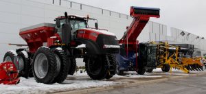 A group of large tractors parked outside of a building.