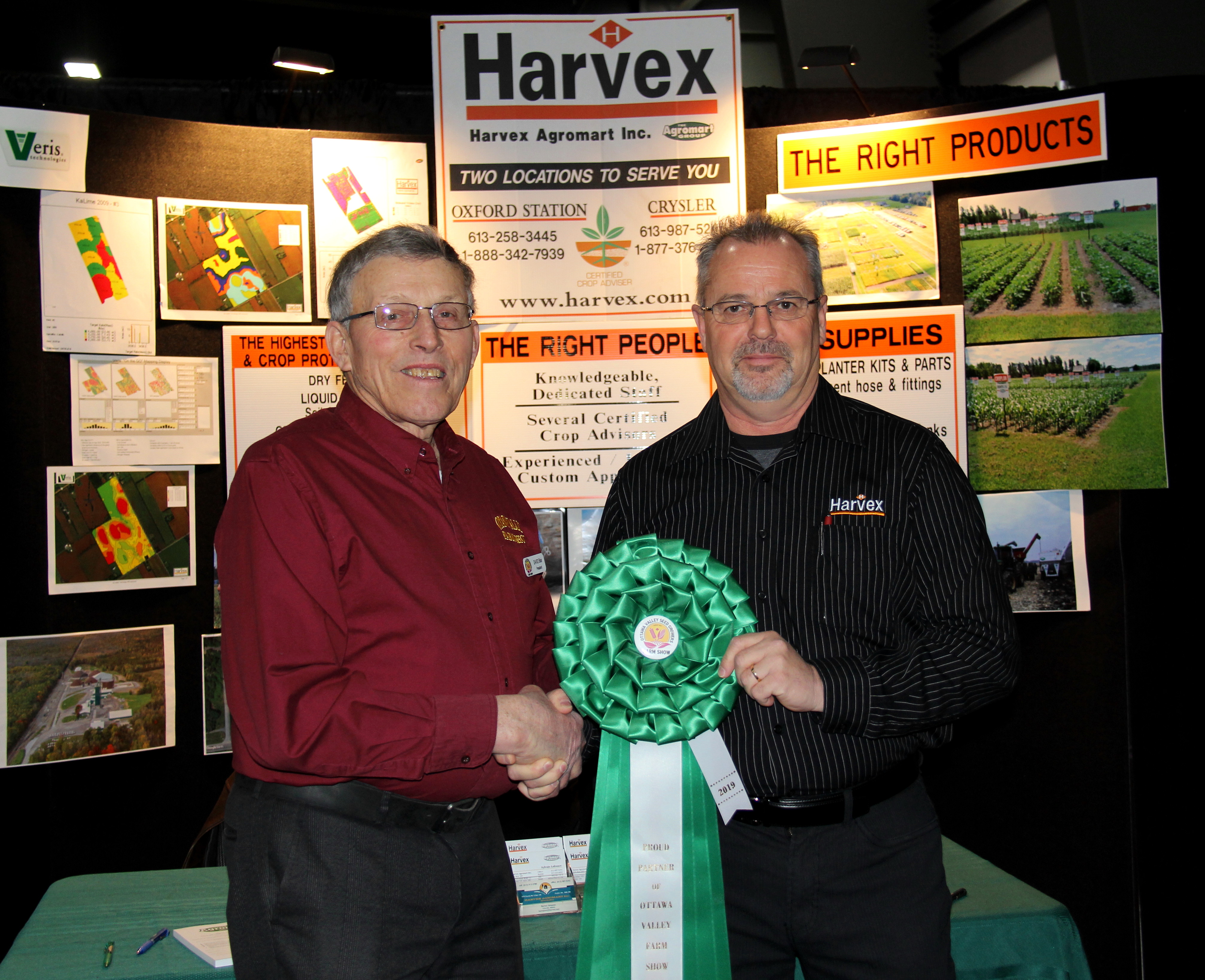 Two men are shaking hands over a green ribbon.