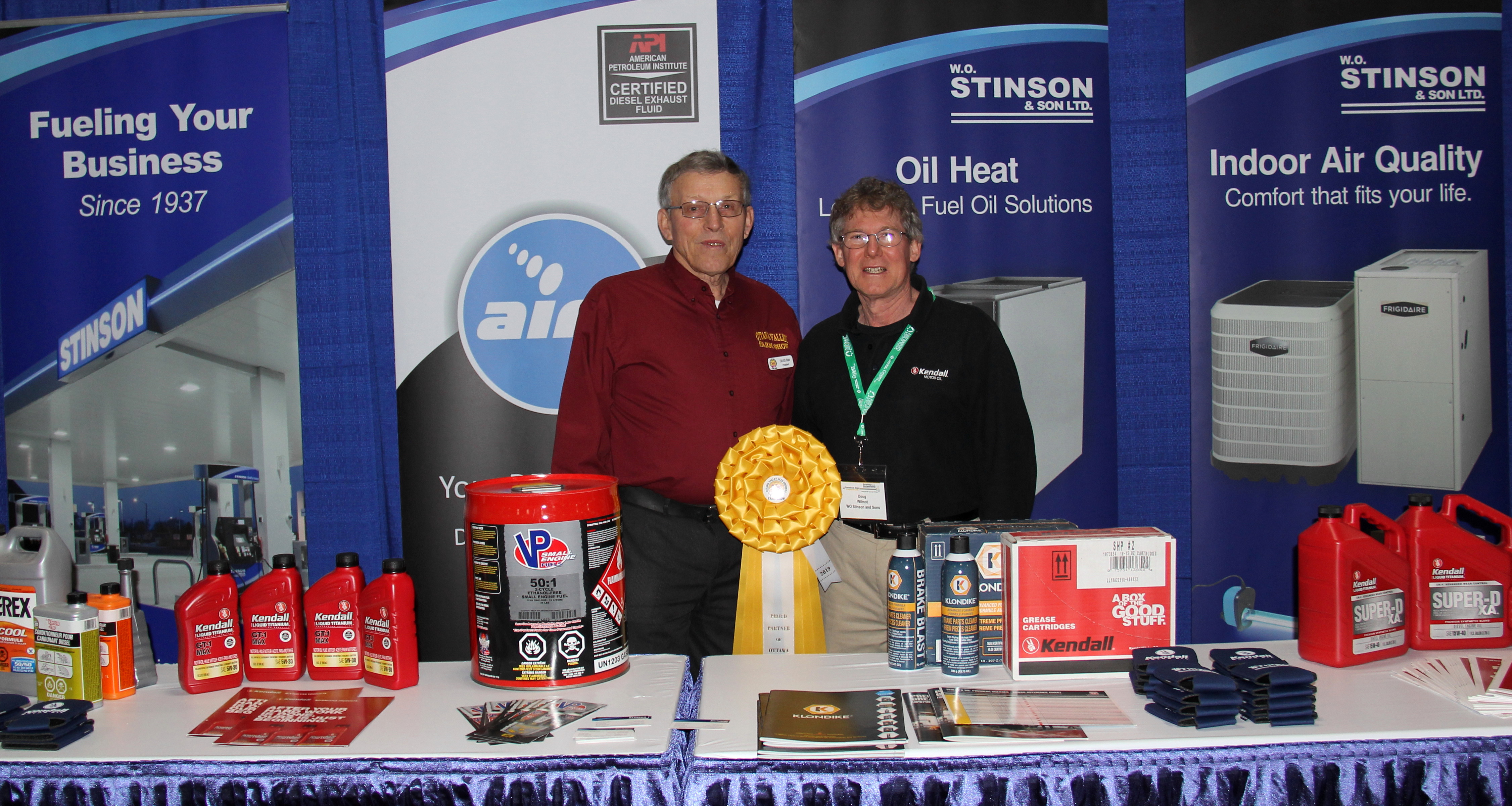 Two people standing in front of a table with oil heat products.