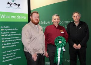 Three men standing in front of a green wall.