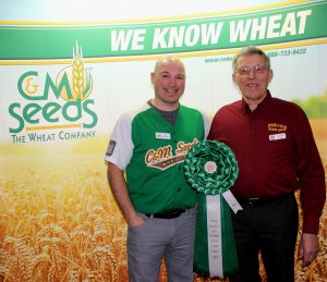 Two men standing in front of a sign with wheat on it.