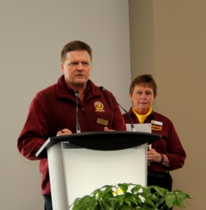 Two people standing at a podium in front of a plant.