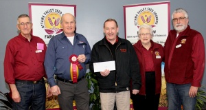 Three people holding a check and one person is holding a ribbon.