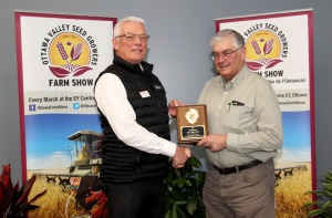 A man holding a plaque is standing next to another man.