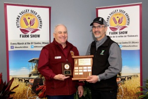 Two men holding a plaque and one man is standing next to the other.