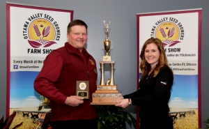 Two people holding a trophy and some awards