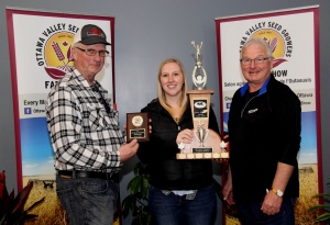 A woman holding a trophy standing next to two men.