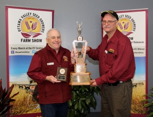 Two men holding a trophy and some awards