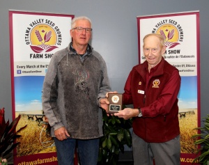 A man standing next to another man holding a plaque.