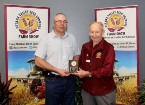 A man standing next to another man holding a plaque.