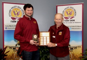 Two men holding a plaque and one man is standing next to the other.