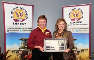 Two women holding a tray of food in front of farm show signs.