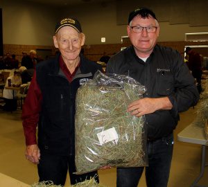 Two men holding a bag of hay.