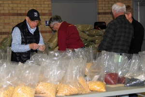 A group of people standing around bags filled with food.