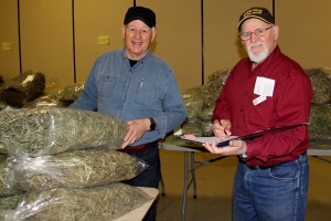 Two men standing next to each other in front of a table full of marijuana.