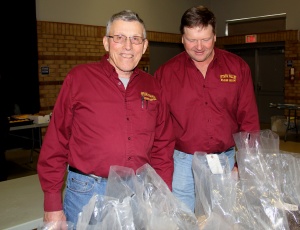 Two men standing next to a table full of bags.