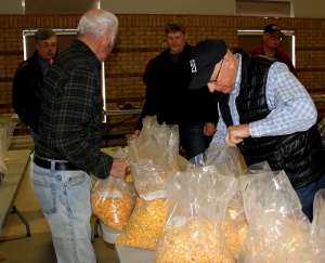 A group of people standing around bags filled with popcorn.