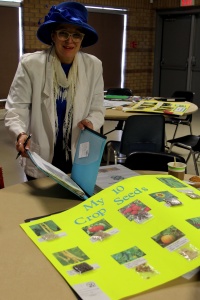 A woman standing next to a table with a poster of plants.