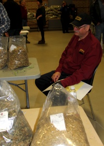 A man sitting at a table with bags of wood shavings.