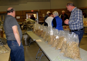 A group of people standing around tables filled with bags.