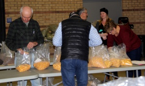 A group of people standing around tables with bags.